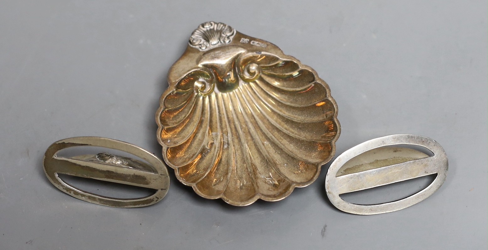 A pair of silver menu card holders, each decorated with a pheasant, Sampson Mordan & Co, Chester, 1907, width 59mm and a silver butter shell.